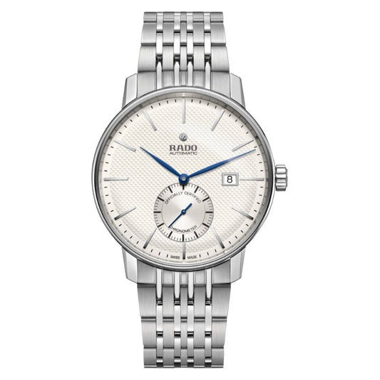 The RADO Coupole Classic Automatic 41mm Watch showcases a textured white dial adorned with blue hands and a date window positioned at 3 o'clock. It features an automatic movement, complemented by a subdial above the 6 o'clock marker, all safeguarded by sapphire crystal. The watch's polished steel bracelet and minimalist hour markers contribute to its sophisticated design.
