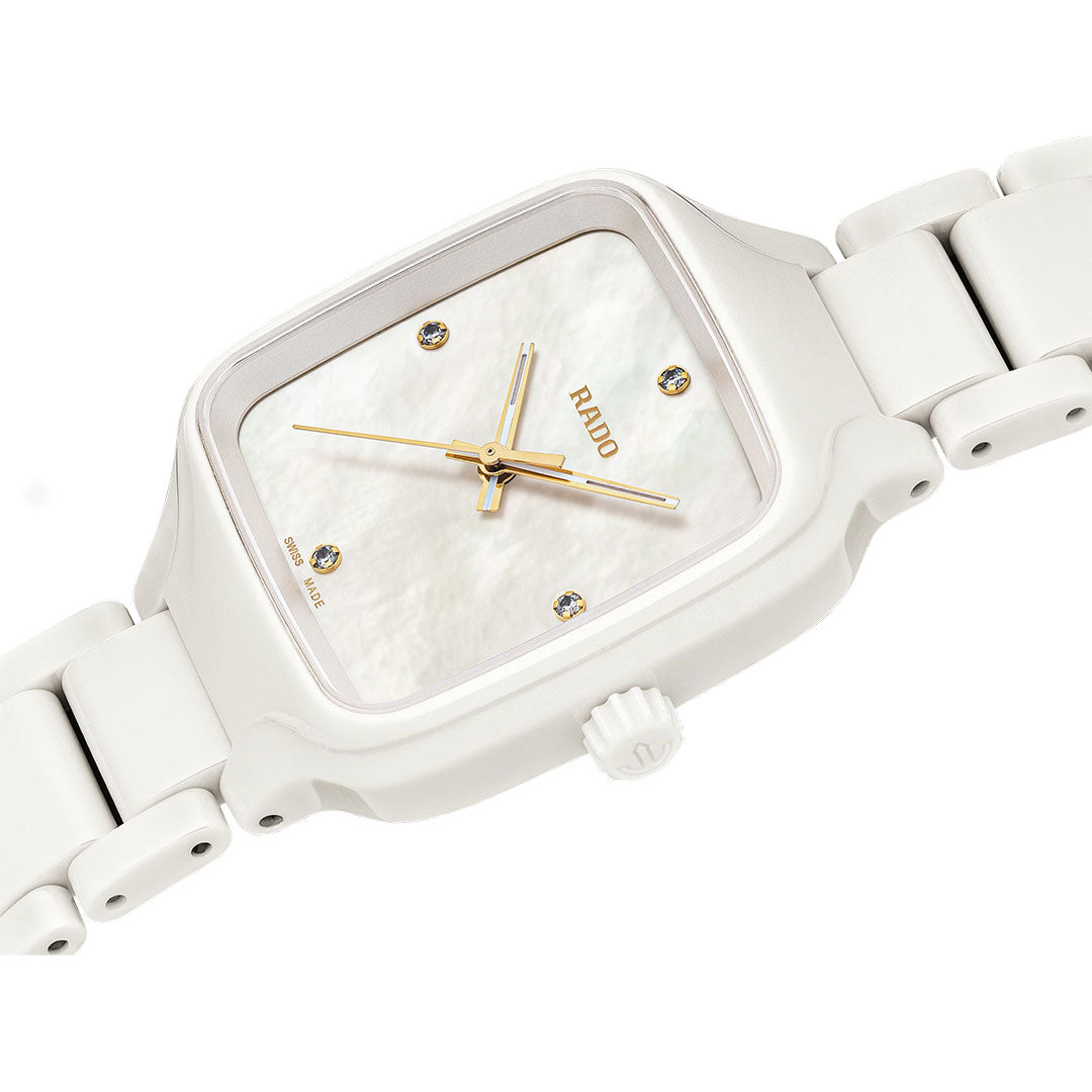 The RADO True Square Diamonds Quartz 29mm Watch features a white high-tech ceramic link band, rectangular face, gold hands, four diamond hour markers, and a minimalist dial in a sleek modern design.