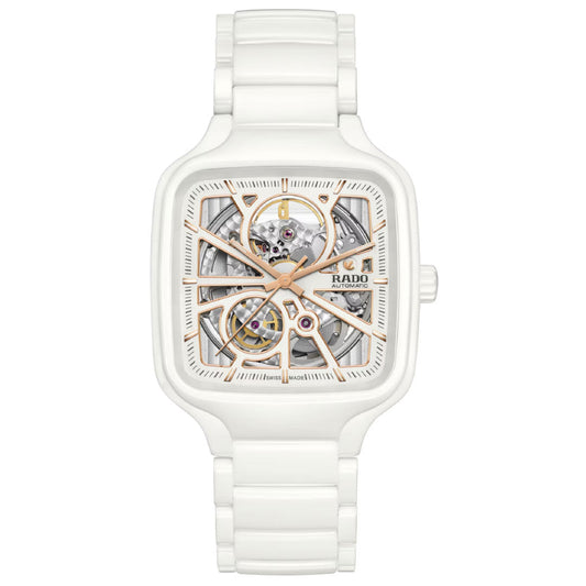 The RADO True Square Automatic Open Heart 38mm watch features a white high-tech ceramic case, square face, exposed skeleton dial with gold-tone details, showcasing inner gears and the "RADO" logo on the right.