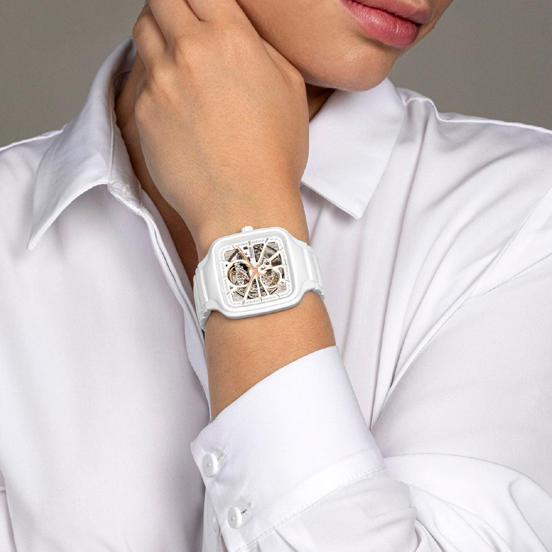 A person in a white dress shirt wears the RADO True Square Automatic Open Heart 38mm Watch by RADO on their left wrist.
