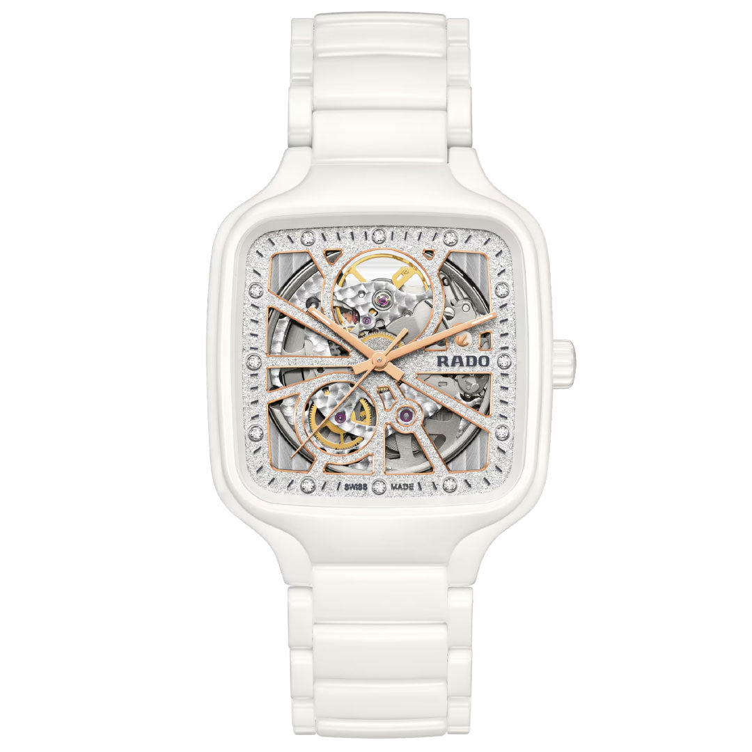 The RADO True Square Automatic Open Heart Sparkling 38mm watch features a square white ceramic case and band, automatic movement, skeleton dial showcasing intricate details, and refined rose gold accents.