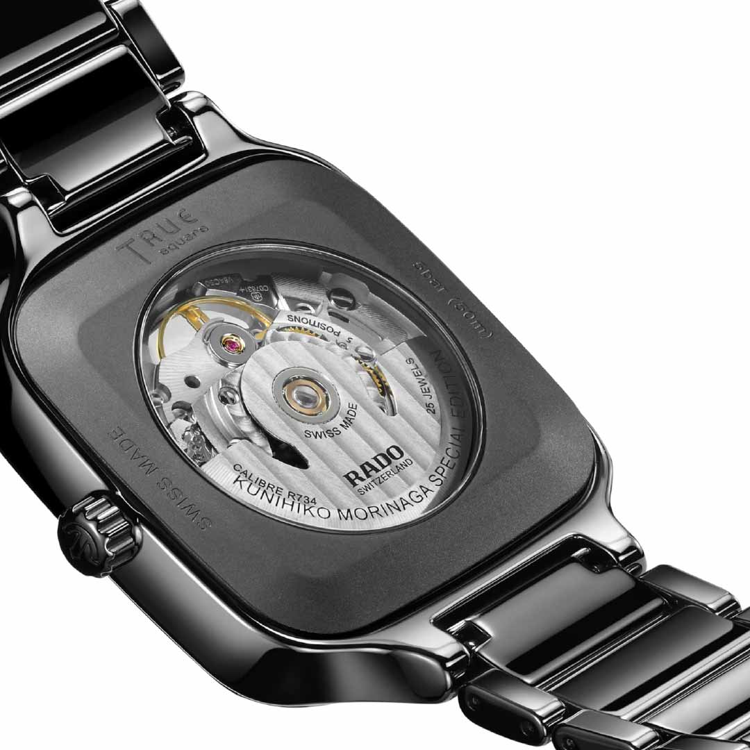 Close-up of the back of a RADO True Square X Kunihiko Morinaga Special Edition Automatic 38mm Watch, highlighting its visible mechanical movement with gears and engravings. The watch features a sleek high-tech ceramic case and bracelet. "RADO" and other details are engraved on the back, reflecting Kunihiko Morinaga's innovative touch.