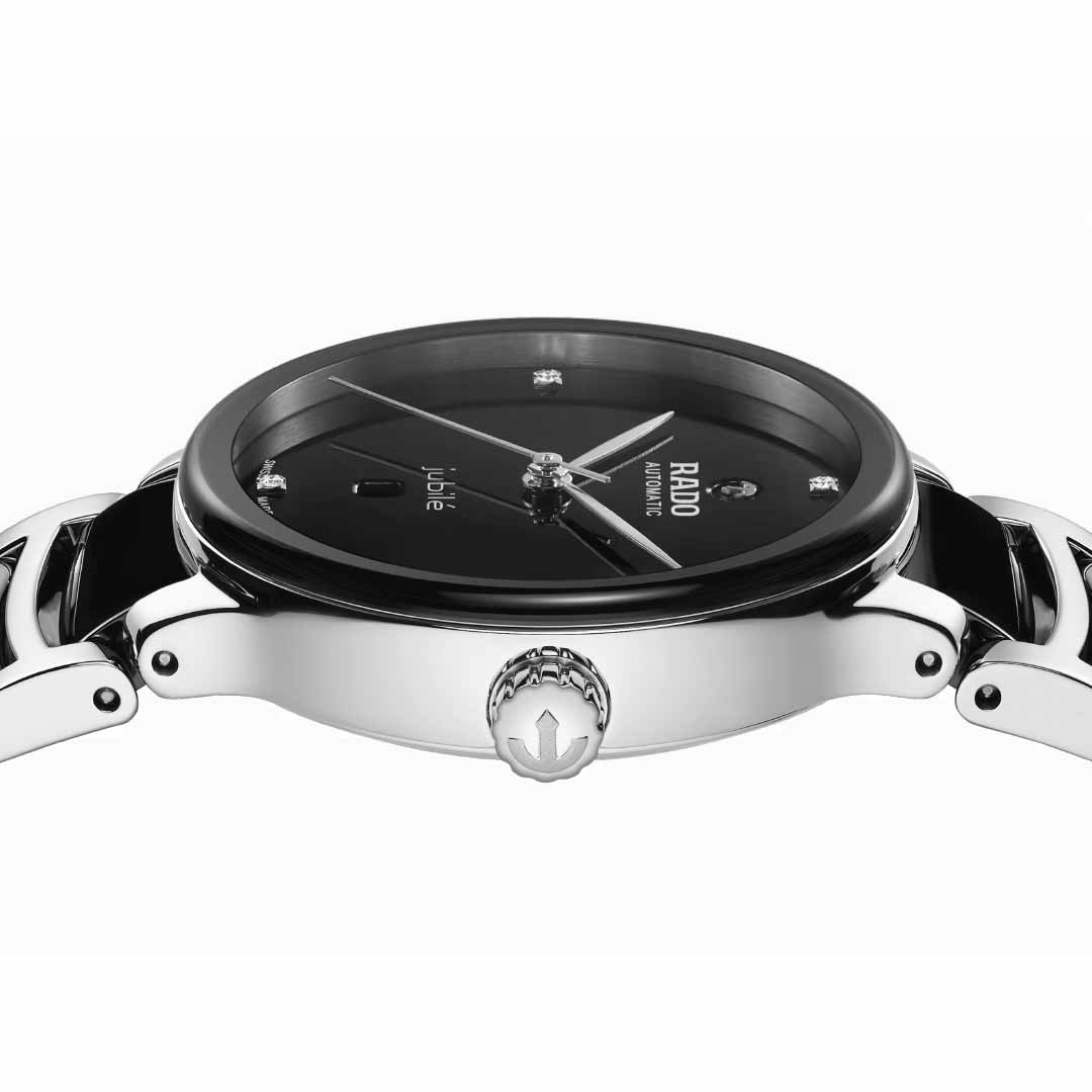 A side view showcases the elegant RADO Centrix Diamonds Automatic 30.5mm Watch, featuring a sophisticated black face adorned with diamond hour markers. The watch's sleek design includes a silver crown and a band crafted from high-tech ceramic combined with black elements, proudly bearing the "Jubile" inscription on its antimagnetic Nivachron™ hairspring face.