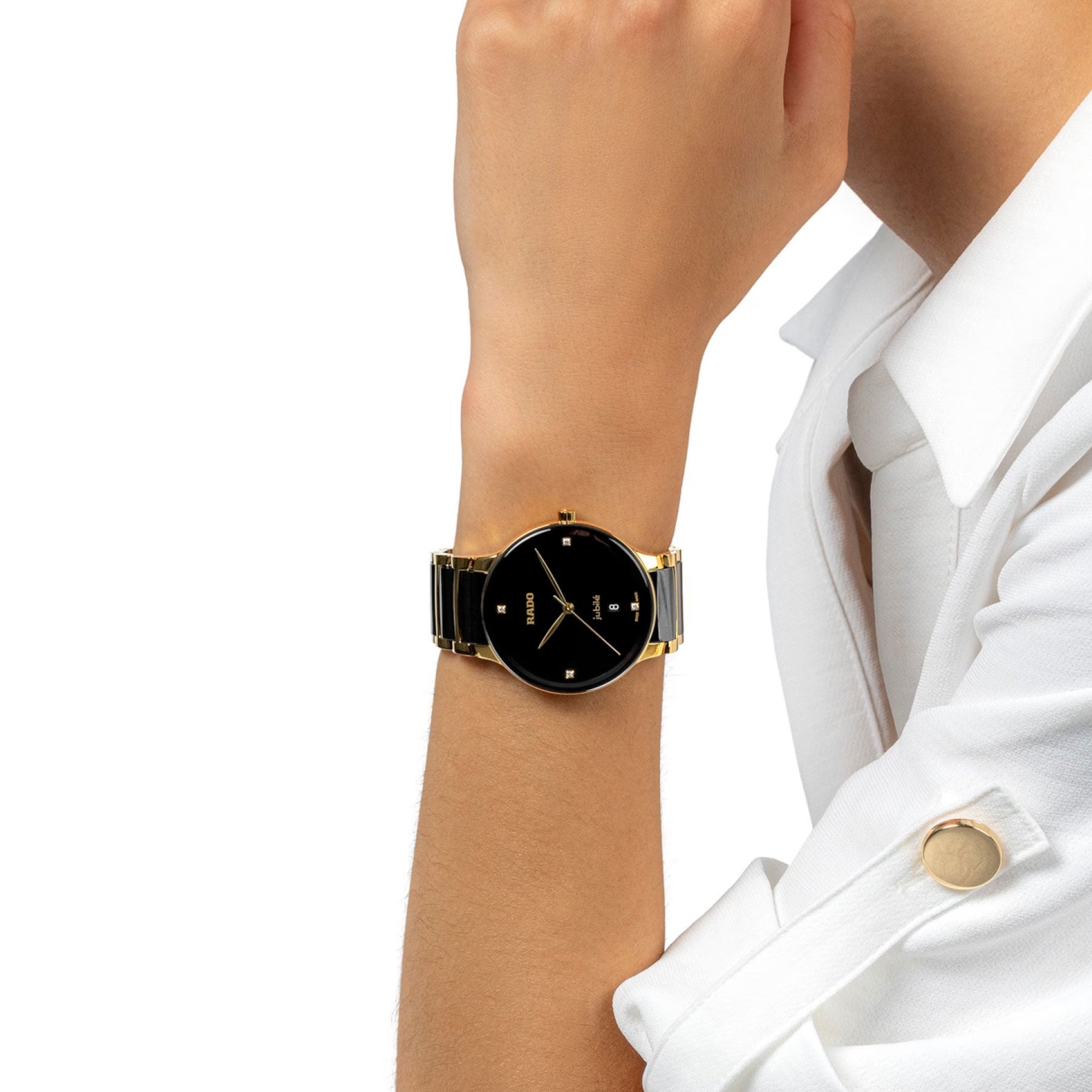 Dressed in a white jacket, an individual displays the refined RADO Centrix Diamonds Quartz 39.5mm Watch. This elegant timepiece is characterized by its minimalist round black face, slender gold hands, and a sophisticated gold and black band. The arm is positioned to highlight the watch prominently.