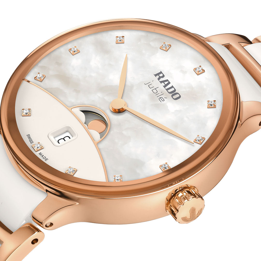 A close-up of the RADO Centrix Moonphase Quartz 35mm Watch, featuring a rose gold case, white high-tech ceramic accents, diamond hour markers, mother-of-pearl dial, and date display at 6 o'clock.