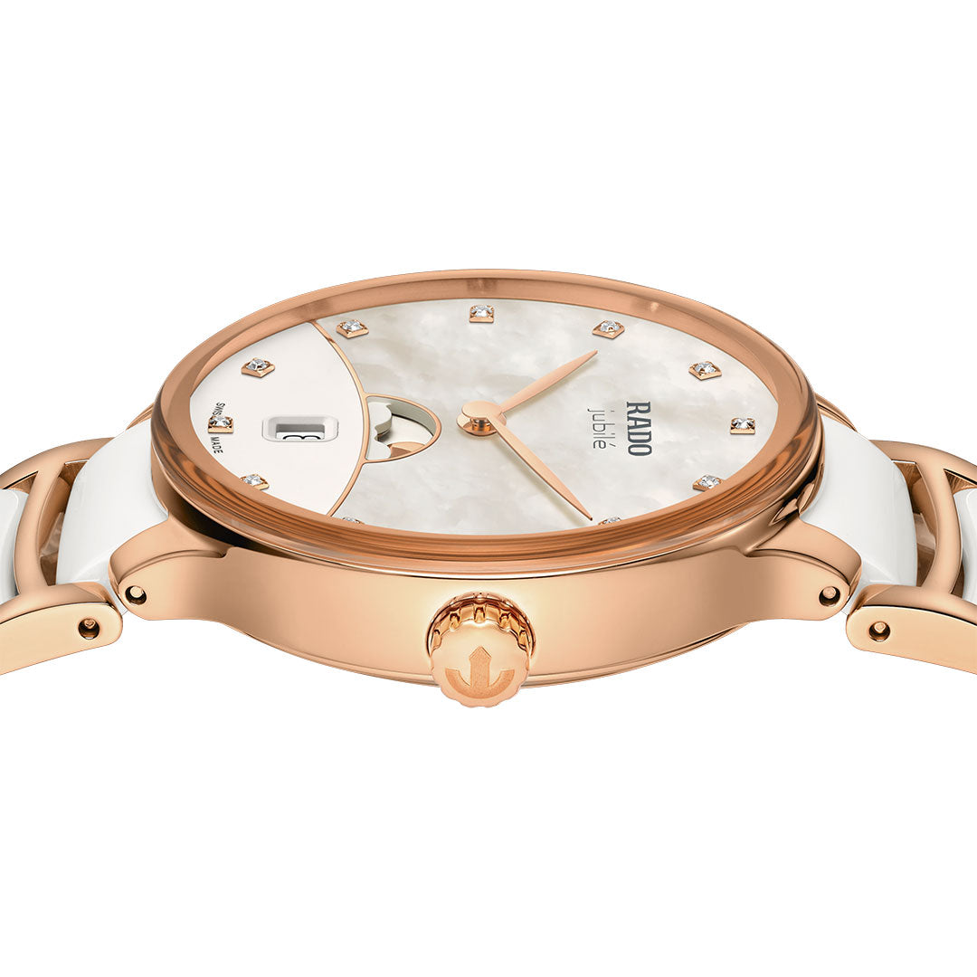 A close-up side view of the RADO Centrix Moonphase Quartz 35mm Watch in rose gold, featuring a white band, diamond hour markers, date display, textured white dial, and high-tech ceramic elegance.