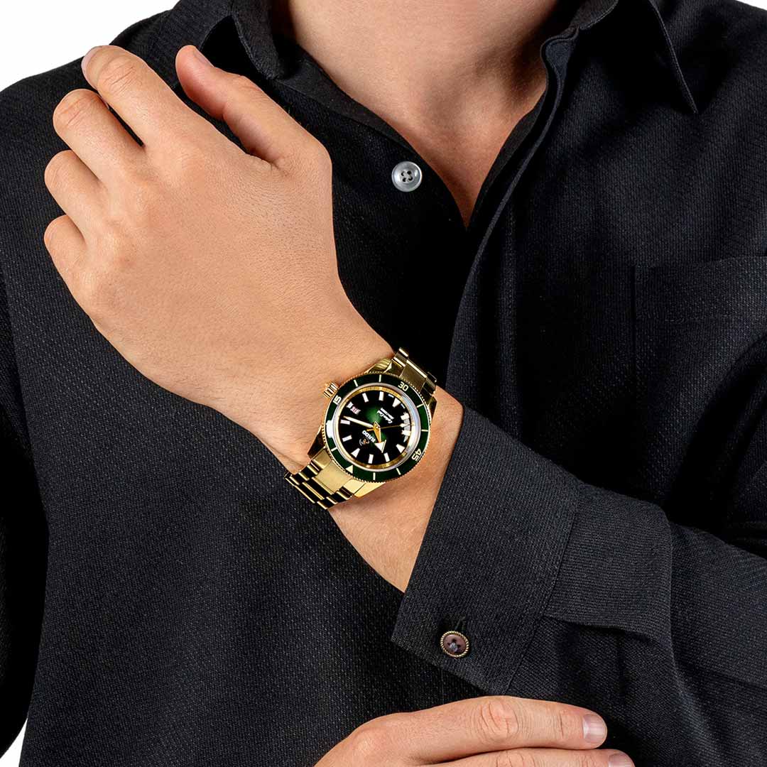 A person in a black shirt adjusts their RADO Captain Cook Automatic 42mm Watch, featuring a gold design and a black dial with white markers. The hand partially crosses the chest, accentuating the watch's elegant design and water resistance.