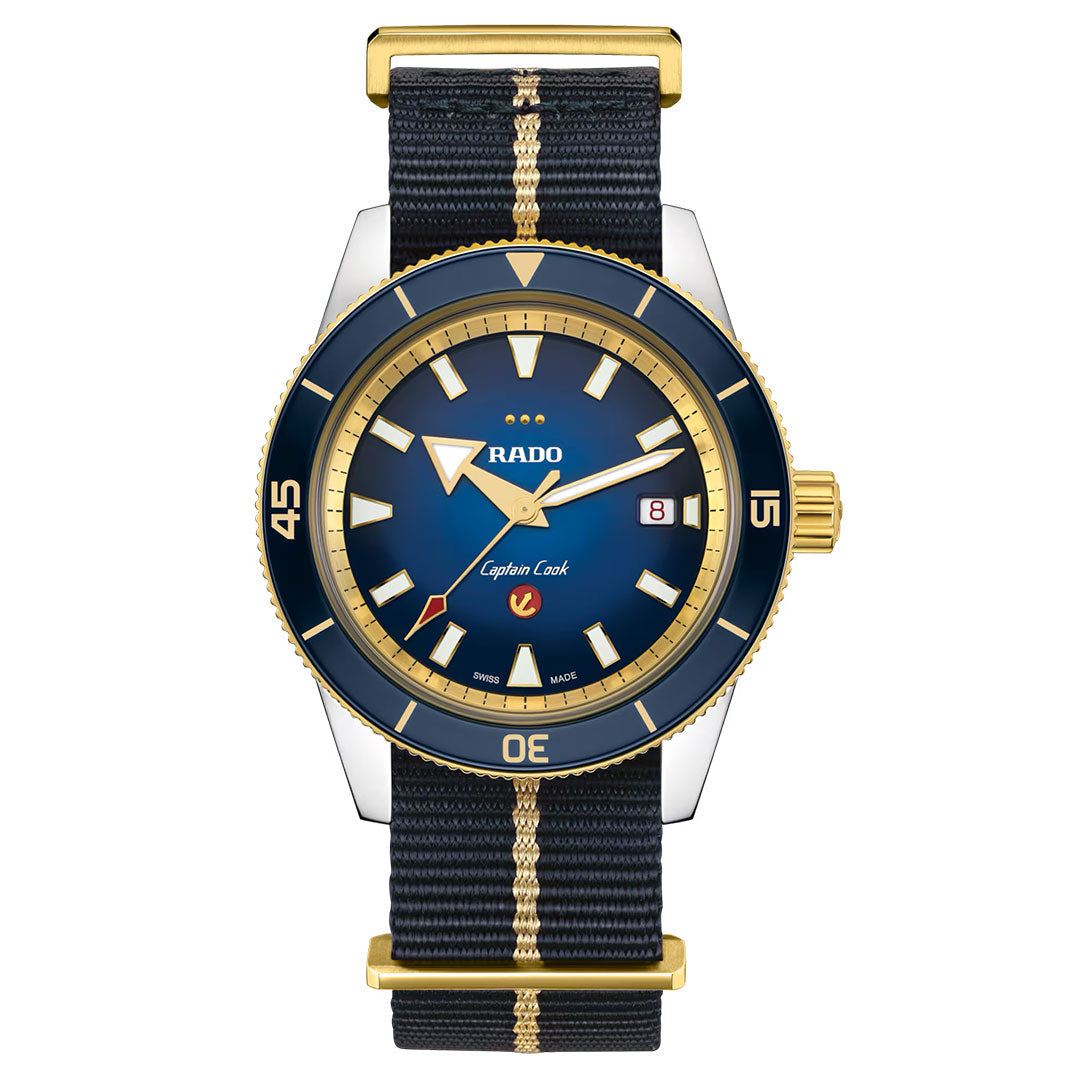 Introducing the RADO Captain Cook X European Cricket Special Edition Automatic 42mm Watch—an elegant timepiece featuring a striking blue and gold bezel, blue dial with gold accents, date display, and a black fabric strap with a gold stripe. Powered by automatic movement from RADO, it ensures precision and reliability.
