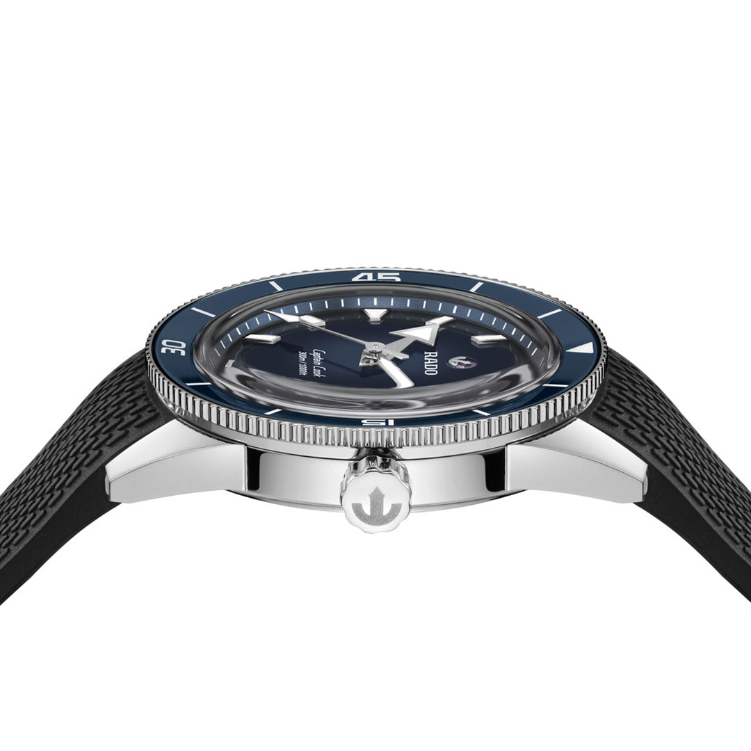 A side view of the RADO Captain Cook Automatic 39mm Watch features a black textured strap, silver case, ceramic bezel, black dial with white markers and hands, prominent crown, and a domed crystal.