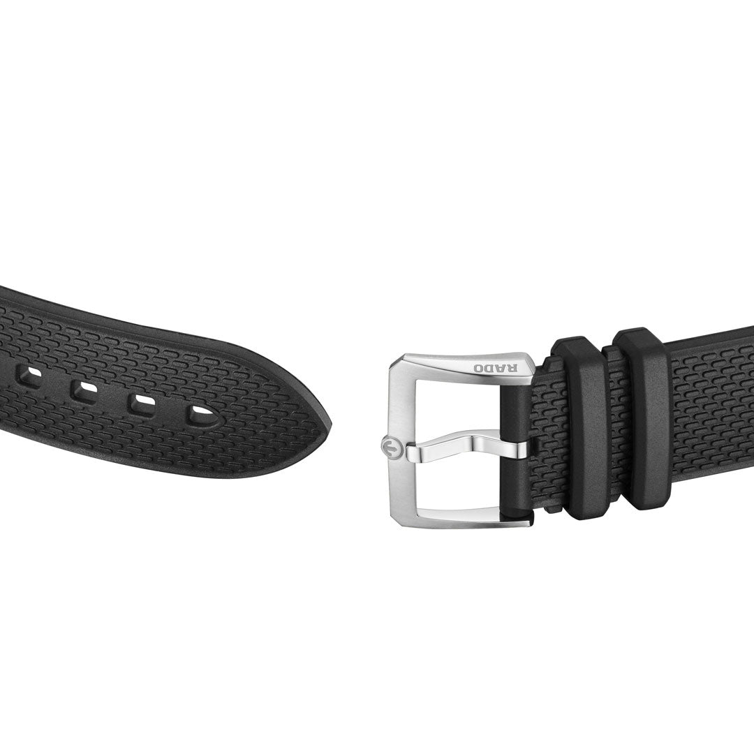 A close-up of a black textured strap with holes at one end and a silver "RADO" buckle at the other, designed for the RADO Captain Cook Automatic 39mm Watch by RADO, shown against a white background.