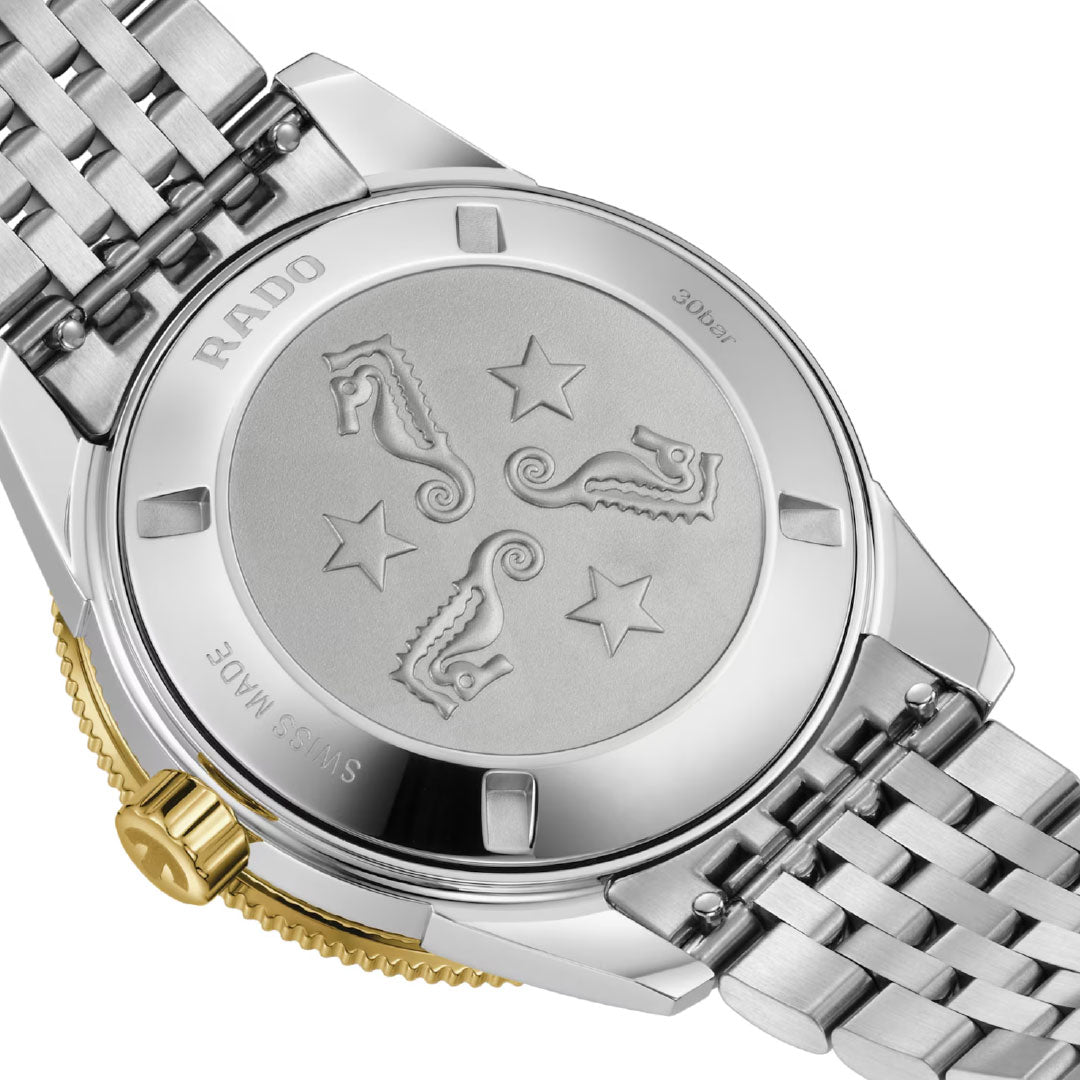 The RADO Captain Cook Automatic 39mm Watch features a stainless steel caseback with engraved seahorses, stars, "SWISS MADE," and "30 bar" markings, plus a gold-toned crown and automatic movement.
