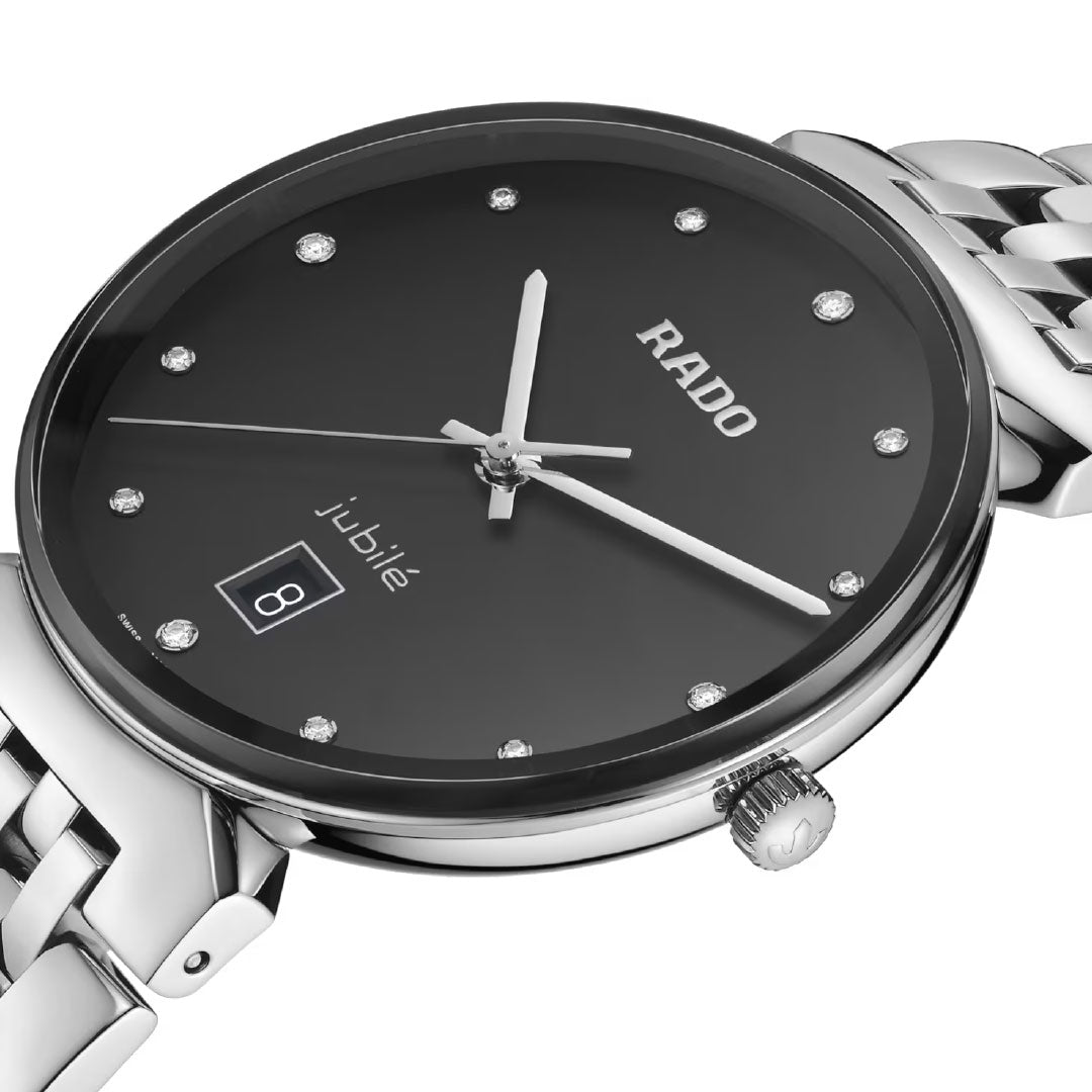 A close-up of the RADO Florence Diamonds Quartz 38mm Watch, featuring a black dial with diamond hour markers, silver hands, date display at 6 o’clock, stainless steel case, metal link band, and a prominent crown.