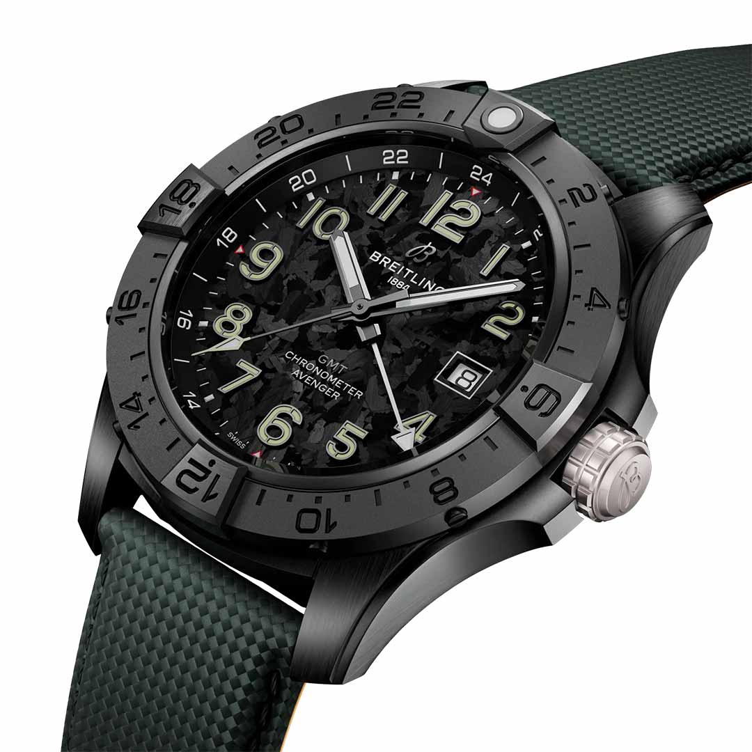 The BREITLING Avenger Automatic GMT 44 Night Mission offers a striking combination of style and functionality, featuring a black wristwatch with a textured black dial, silver hour markers, and a date window. The bezel is engraved with numbers, and it is complemented by an aviation-style green fabric strap.