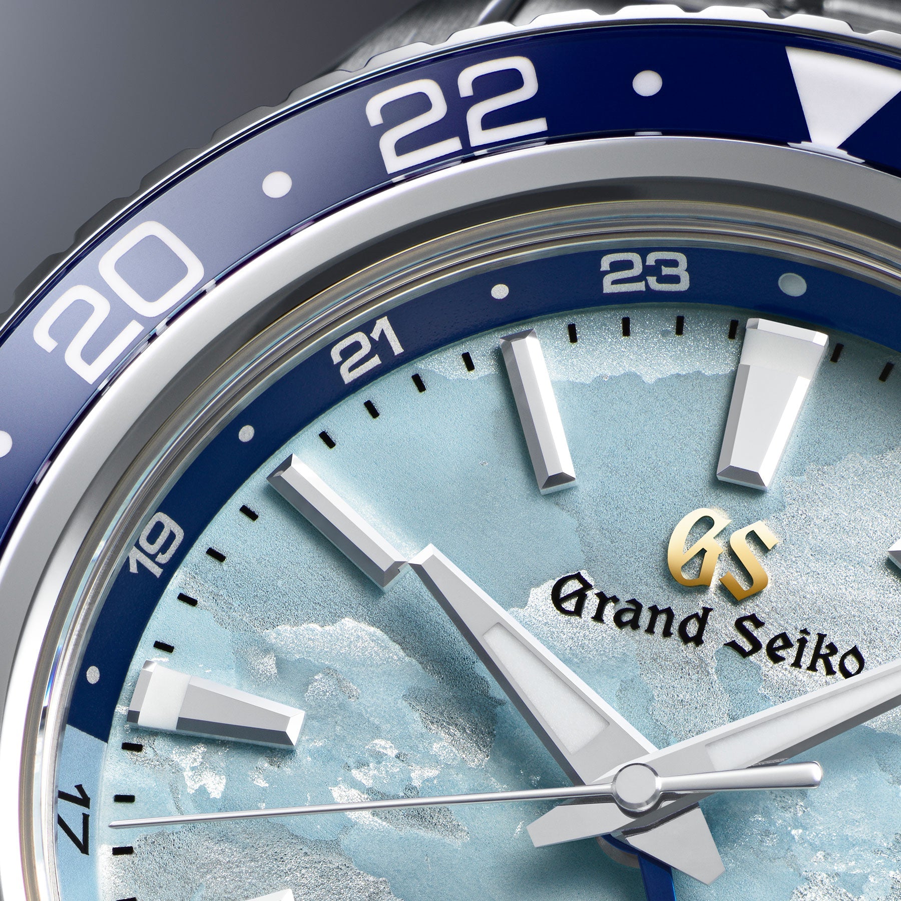 Close-up image of the Grand Seiko Sport Collection Automatic with Manual Winding Mechanical Hi-Beat 36000 GMT 44.2mm Watch, a 25th Anniversary Limited Edition piece, featuring a striking blue and silver design. This exclusive watch, limited to just 2,000 pieces, showcases a wave-patterned background with silver hour markers and a 24-hour bezel. Powered by the Caliber 9S86, it prominently displays the hands and "Grand Seiko" logo.