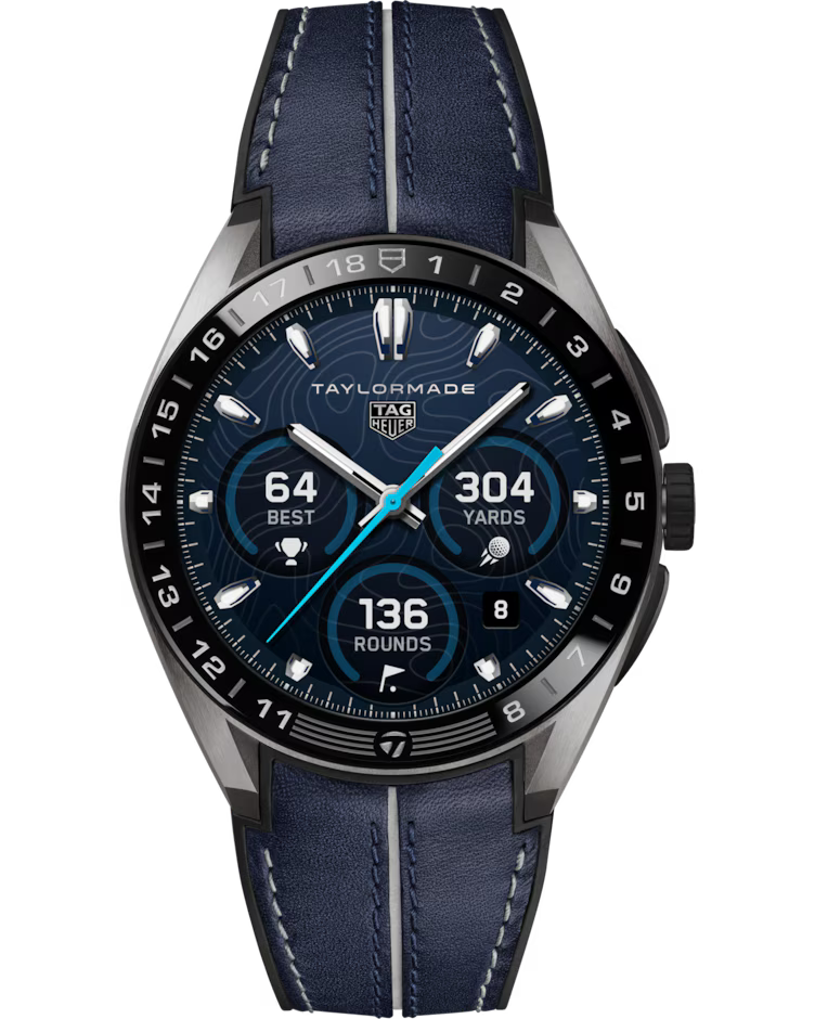 The TAG Heuer Connected Calibre E5 x TaylorMade Edition 45mm Smart Watch features a blue leather strap and displays golf stats such as a best score of 64, 304 yards, and 136 rounds played. The watch face is accented with silver indexes, three subdials, and “TAYLORMADE” branding at the top.
