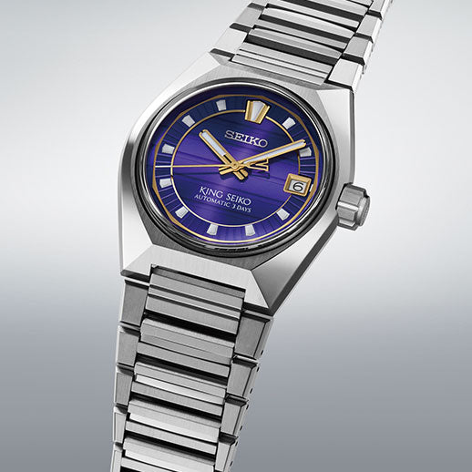 The Seiko King Seiko VANAC Automatic with Manual Winding 41mm Watch features a silver case, metallic bracelet, blue dial, gold hour markers and hands, plus a date window at 3 o'clock, shown on a light gray background.