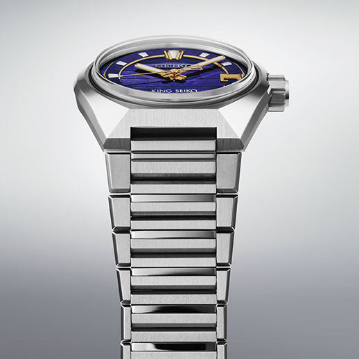 A close-up of the Seiko King Seiko VANAC Automatic with Manual Winding 41mm Watch highlights its angular silver case, blue and gold dial, and metal bracelet from Seiko, set against a light gray background.