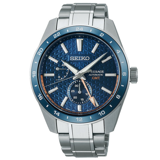The Seiko Presage Automatic With Manual Winding 42.2mm Watch, crafted by Seiko, features a stainless steel band and case. It showcases a textured blue dial adorned with silver hour markers and hands. The design is further enhanced by a GMT sub-dial, date display, and water resistance, with its elegant blue and silver bezel contributing to its sophisticated charm.