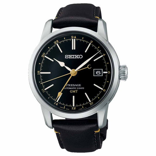 The Seiko Presage Craftsmanship Series Automatic with Manual Winding GMT 40.2mm Watch features a black dial adorned with gold hands and a date window, highlighted by the refined touch of urushi lacquer. It is encased in silver and paired with a sleek black leather strap, offering both GMT and standard time markers for exceptional precision and style.