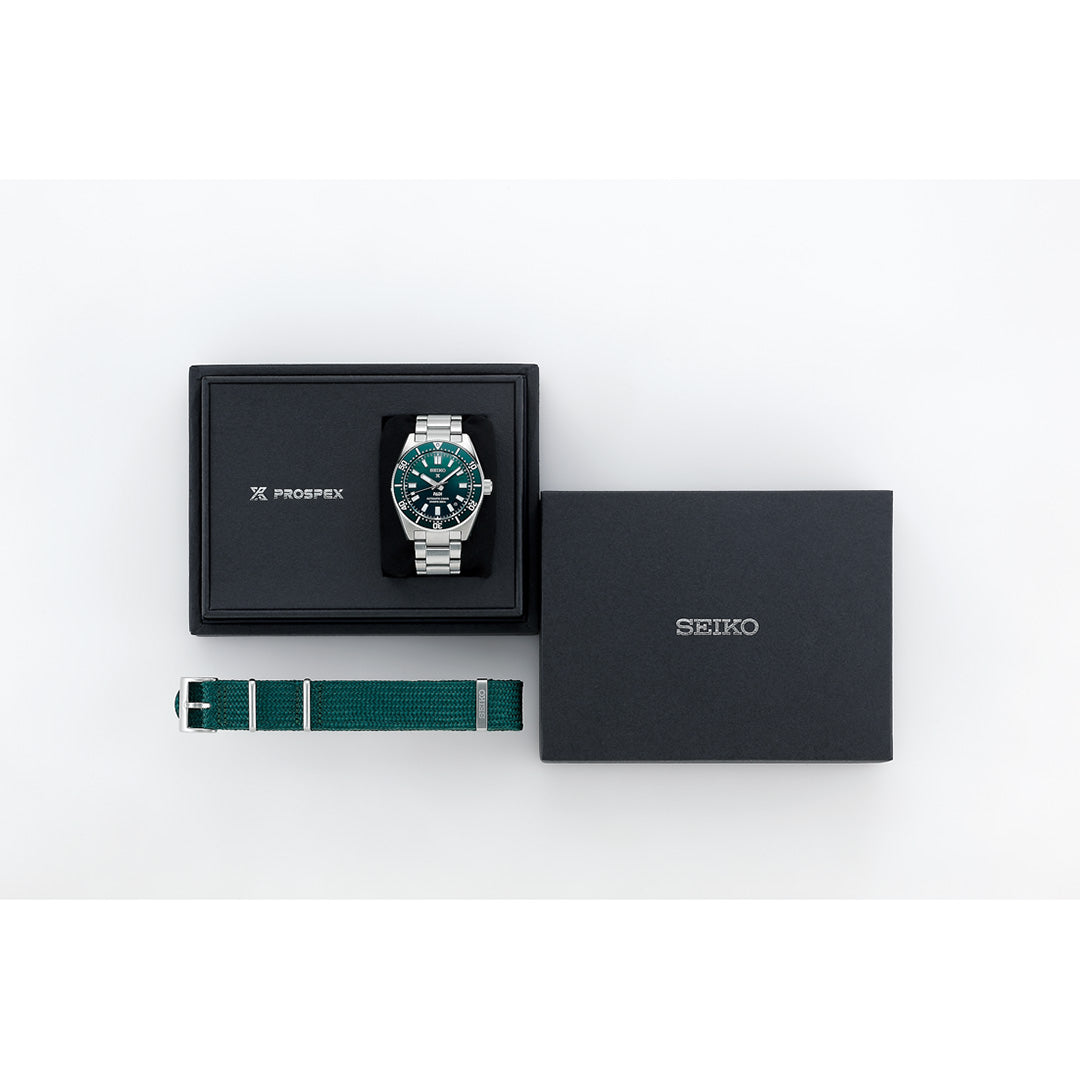 A Seiko Prospex Sea Automatic 40mm Watch by Seiko, featuring a vibrant green dial and a stainless steel silver band, is displayed in an open black box beside a green fabric strap and an additional closed black Seiko box, all arranged on a white background.