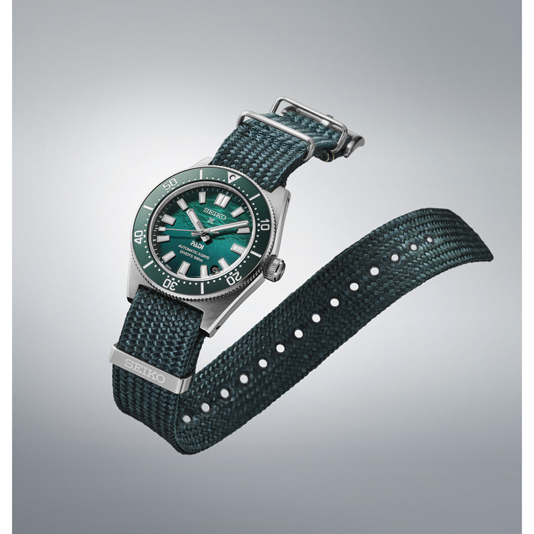 The Seiko Prospex Sea Automatic 40mm Watch by Seiko is showcased with a matching green textured strap against a gray gradient background. Its 40mm stainless steel case with silver accents highlights the bold green bezel and dial. Combining durability and style, this automatic timepiece is ideal for everyday adventures.