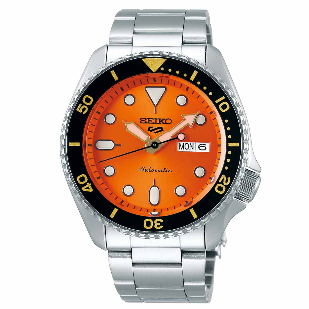 The Seiko 5 Sports SKX Series Automatic 42.5mm Watch boasts a silver design and a vibrant orange face, complemented by a black bezel and silver hour markers. This watch features 100m water resistance and automatic movement, with "Seiko" prominently displayed on the dial alongside day and date functions. Luminous hands add to its sleek appearance.