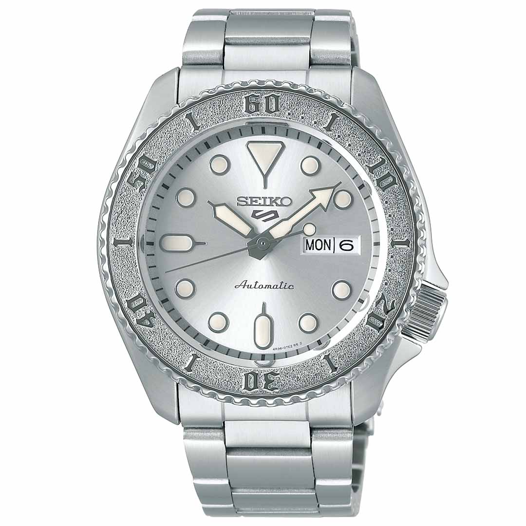 Seiko's SKX Series 5 Sports Automatic 42.5mm Watch showcases a stainless steel case with a metallic bezel, luminous hour markers and hands, featuring an automatic movement alongside a day and date display located at the 3 o'clock position. This sophisticated timepiece is complemented by a sleek stainless steel bracelet.