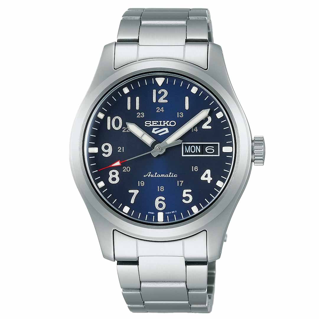 The Seiko 5 Sports Field Series Automatic 39.3mm Watch by Seiko features a sleek silver design with a stainless steel bracelet. Its dark blue dial includes white numerals and showcases the day and date on the right, highlighted by silver hands and a red-tipped second hand.