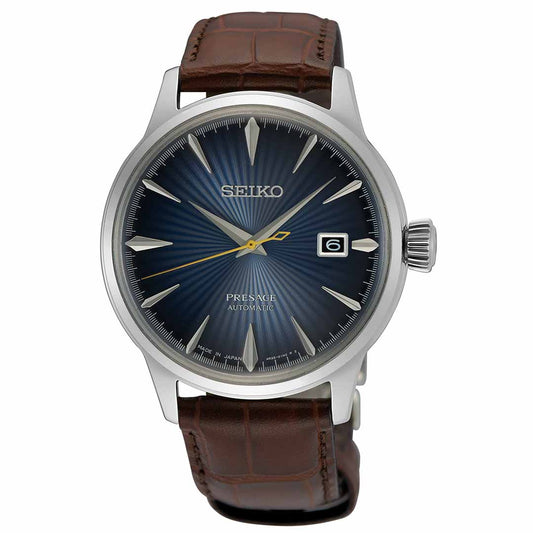 The Seiko Presage Cocktail Time Automatic 40.5mm Watch by Seiko features a stunning blue textured dial adorned with silver indices and a gold second hand. Its automatic movement is beautifully encased in stainless steel, paired with a brown leather strap, and includes a date window positioned at 3 o'clock.