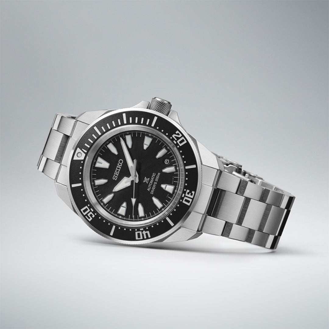 The Seiko Prospex Diver's Automatic 42mm Watch, by Seiko, is a sleek silver wristwatch featuring a black dive bezel and dial, complemented by a stainless steel band. Set against a light gray background, this diver's watch boasts large white hour markers and showcases a bold, sporty design with automatic movement.