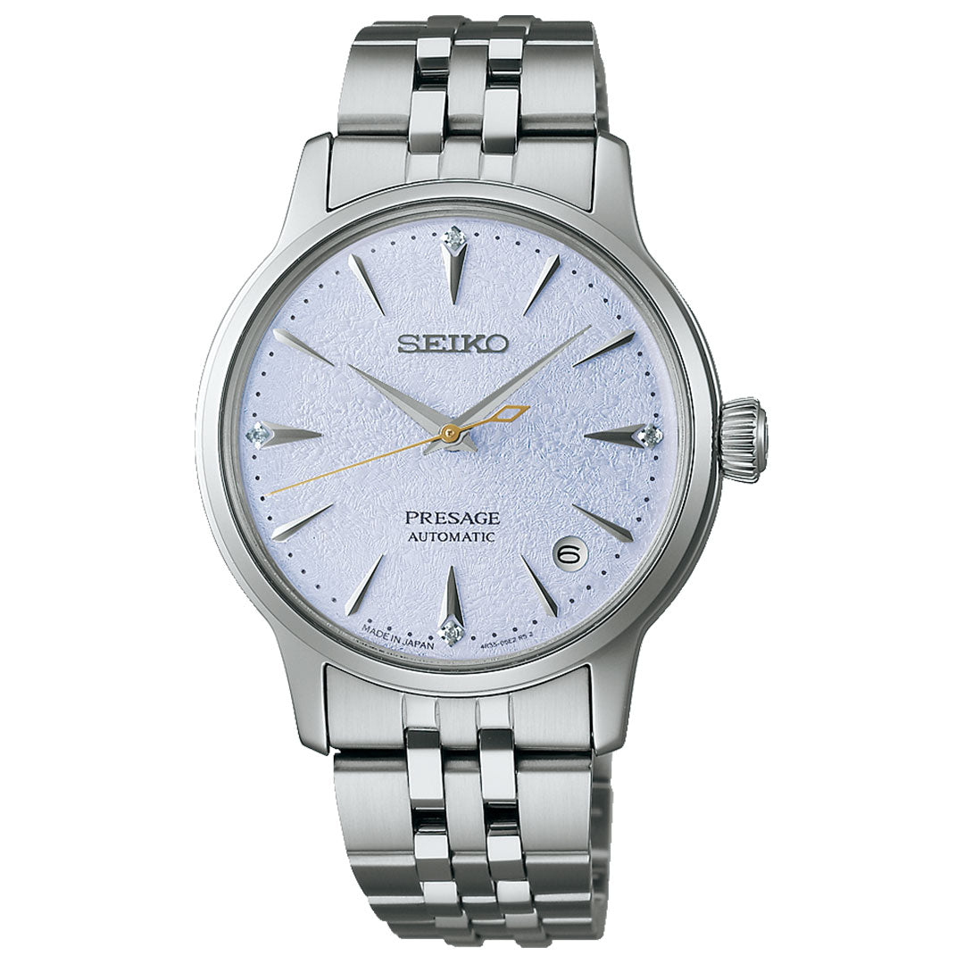 The Seiko Presage Cocktail Time Automatic 34mm watch features a textured light blue dial, silver markers, gold second hand, date at 3 o’clock, and a metal link bracelet.