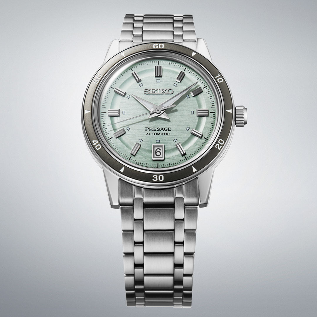 The Seiko Presage Style 60's Automatic with Manual Winding 39.5mm Watch features a mint green dial, silver hour markers, and a date at 6 o’clock, displayed against a light grey background.