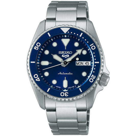 The Seiko 5 Sports SKX Series Automatic 38mm Watch by Seiko features a blue dial, silver hour markers, stainless steel band, and day-date display at the 3 o'clock position.