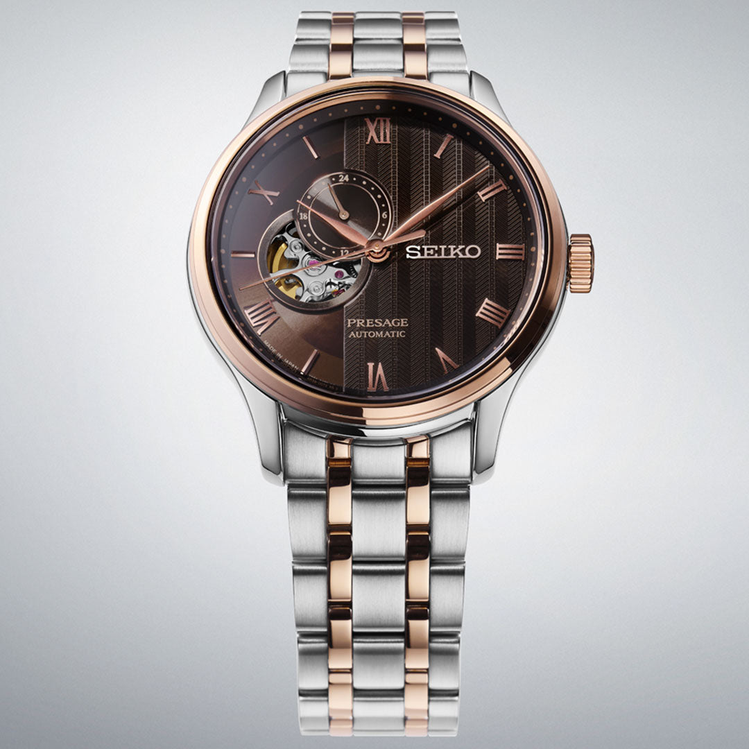The Seiko Presage Japanese Garden Automatic 41.8mm Watch features a brown dial, visible mechanism, rose gold Roman numerals, and a two-tone silver and rose gold bracelet, displayed against a light gray background.