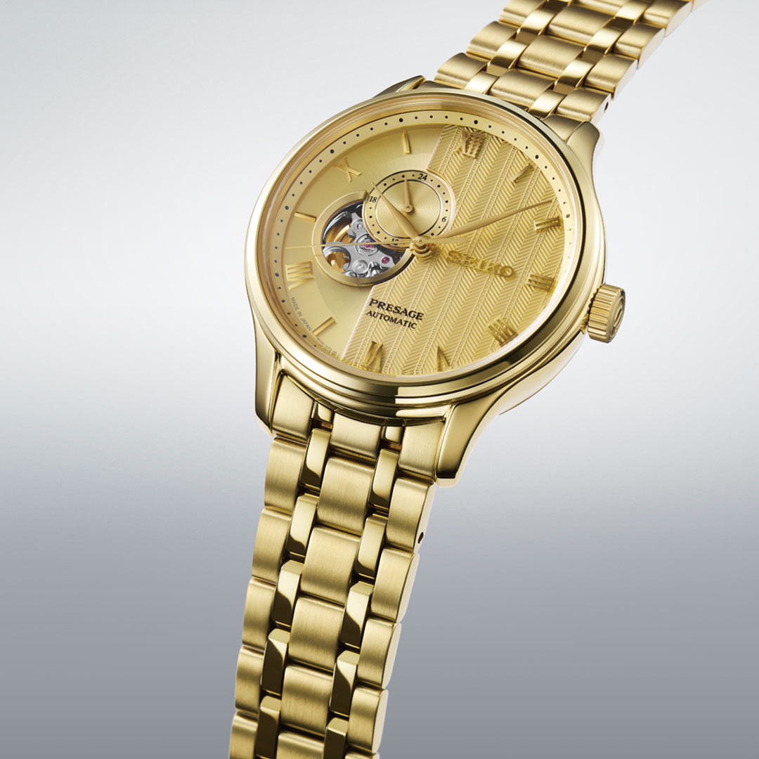 The Seiko Presage Japanese Garden Automatic with Manual Winding 41.8mm Watch features a gold-tone metal link band and an open-heart textured gold dial, showcased against a light gray background.