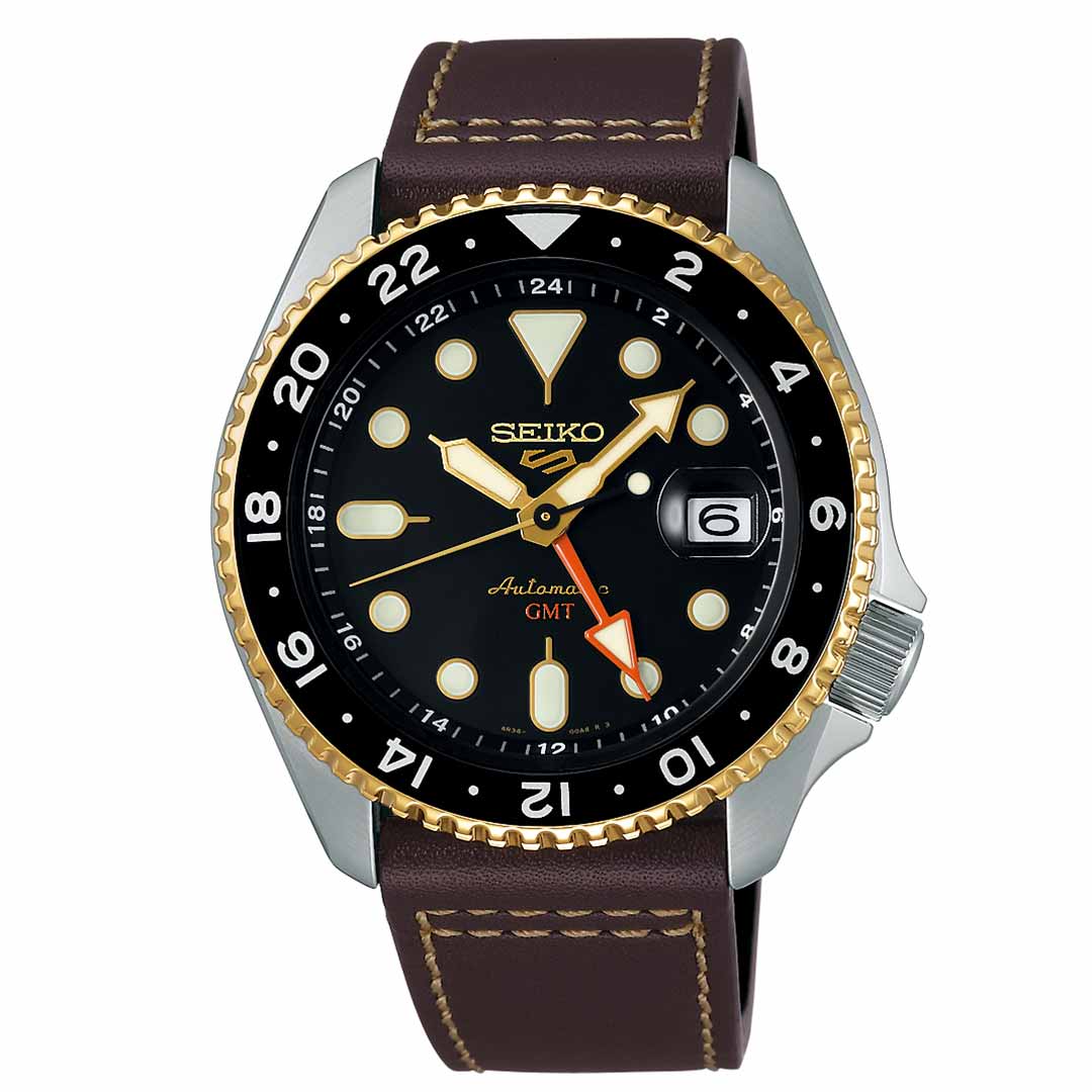 Introducing the Seiko 5 Sports SKX Series Automatic 42.5mm Watch by Seiko, which features a sleek black dial adorned with gold and silver accents, complemented by large round and triangular markers. It comes with a stylish brown leather strap and is equipped with a bezel featuring a 24-hour GMT scale. Designed for everyday wear, it offers water resistance and includes an automatic movement with a date window located at the 3 o'clock position.