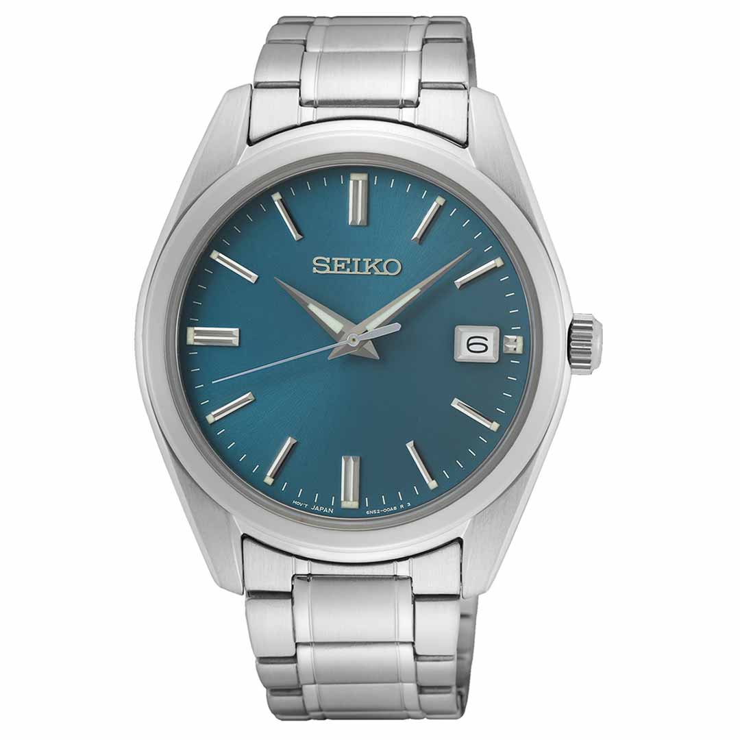 The Seiko Essentials Quartz 40.2mm Watch from Seiko features a silver stainless steel band and an eye-catching blue dial. It includes silver hour markers and hands, a date display positioned at 3 o'clock, and a crown on the right side, all encased in durable sapphire crystal.