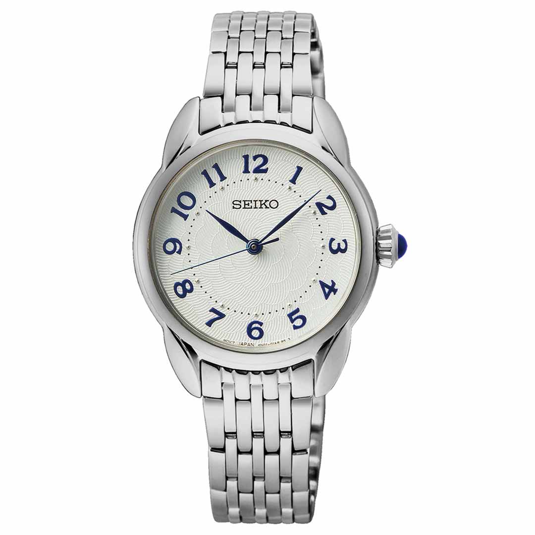 The Seiko Essentials Quartz 28.7mm Watch by Seiko features a stainless steel band, a round white face adorned with blue Arabic numerals, and elegant black hour and minute hands. A blue-accented crown adds the finishing touch to this classic quartz timepiece.