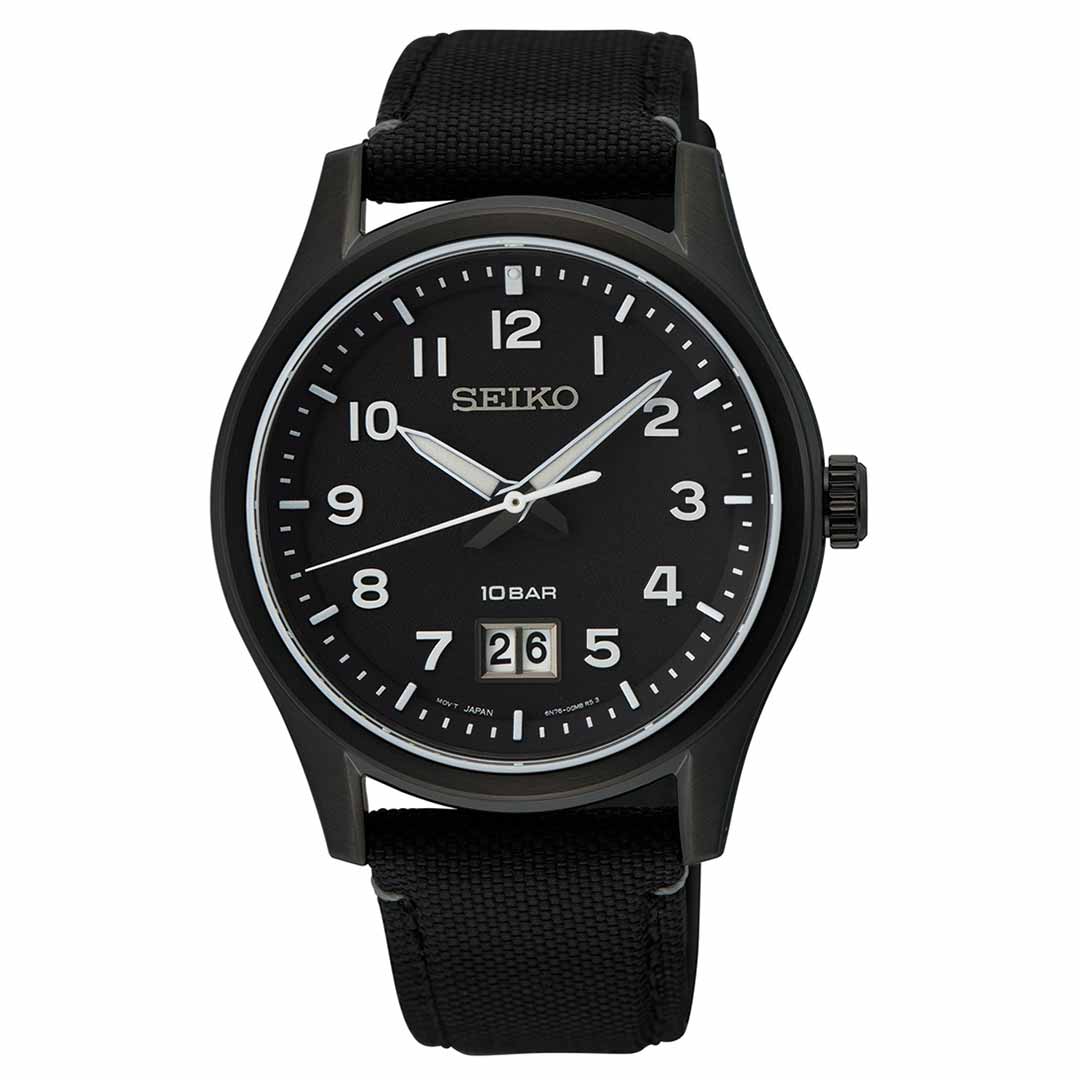 A Seiko Essentials Quartz 39.5mm Watch featuring a black round face with white Arabic numerals and luminous hands, along with a date display at the 6 o'clock position. The watch comes with a premium genuine leather strap and is rated "10 BAR" for water resistance.