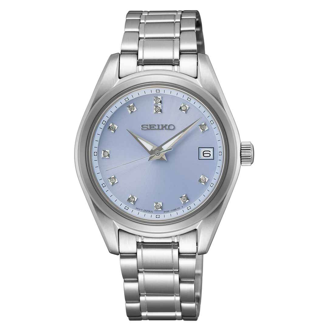 The Seiko Diamonds Quartz 32mm Watch features a stainless steel bracelet and a light blue dial adorned with diamond-like hour markers. It includes a date display at the 3 o'clock position. This silver-toned watch boasts Seiko's Diamonds Quartz movement, and its sapphire crystal enhances the durability of the hands.