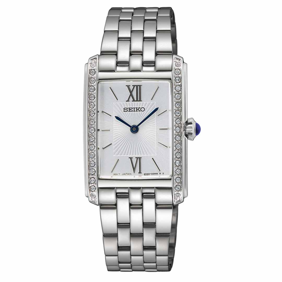 The Seiko Essentials Quartz 22.7mm Watch showcases an elegant design with a silver stainless steel finish, featuring a rectangular face adorned with Roman numerals at 12 and 6. Its bracelet-style band harmoniously complements the crystal-embellished bezel and blue-accented crown, making it a sophisticated accessory for women.