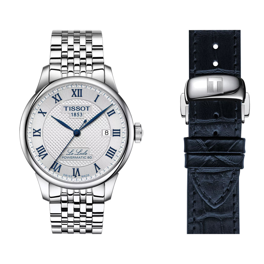 A Tissot Le Locle 20th Anniversary Powermatic 80 Automatic 39.3mm watch with a silver case, white dial, blue Roman numerals, date display, and metal link band is shown beside a dark blue leather strap and clasp.