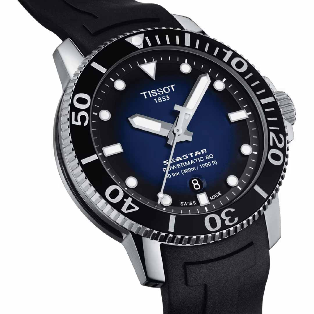 The Tissot Seastar 1000 Powermatic 80 Automatic 43mm Watch boasts a ceramic bezel and a stylish black rubber strap. It features a blue dial with prominent white markers and hands, along with a date window located at the 6 o'clock position, ensuring precision and reliability through its Powermatic 80 automatic movement.