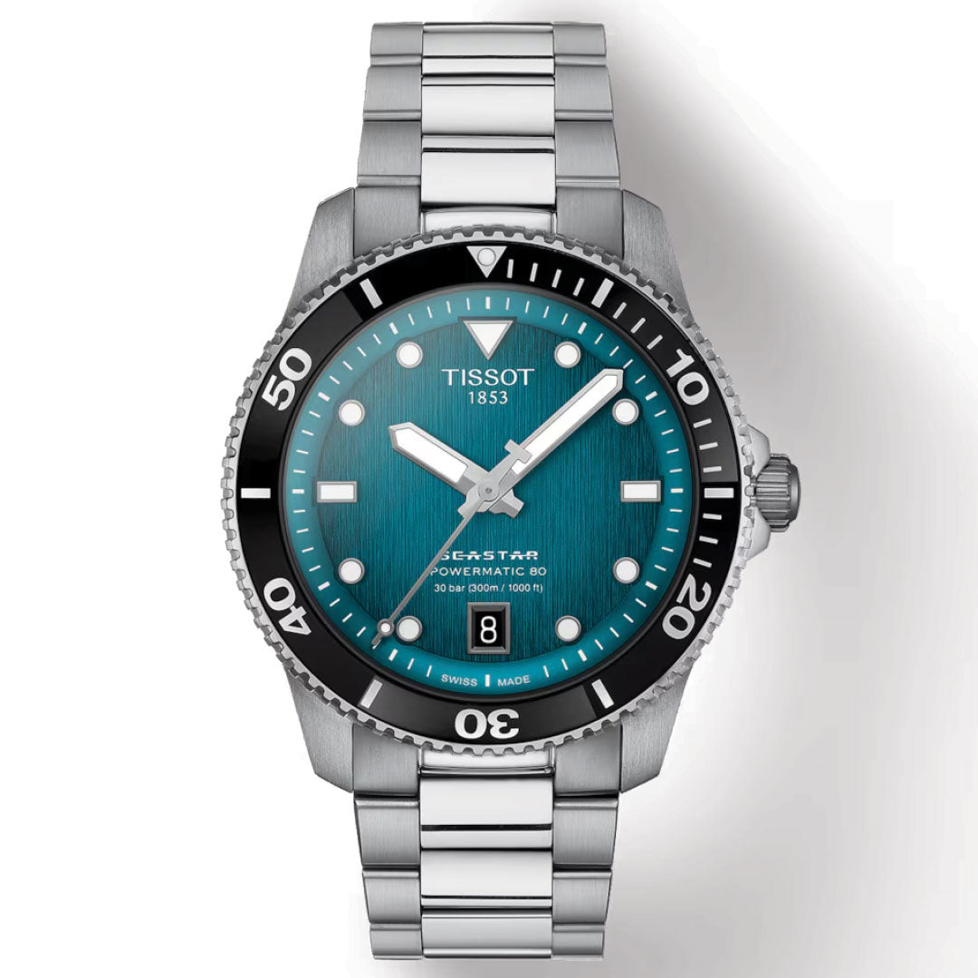 The Tissot Seastar 1000 Powermatic 80 Automatic 40mm Watch showcases a stainless steel band and a striking teal dial. Silver hour markers, enhanced with Super-LumiNova, ensure clear readability. It features a date display and a prominent bezel while the "Tissot 1853" logo adorns the face, powered by the Powermatic 80 movement.