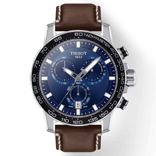 The Tissot Supersport Chrono Quartz 45.5mm Watch for men features a striking blue dial adorned with silver markers and a date display. It is equipped with a brown leather strap, a black tachymeter bezel, and three sub-dials. The stainless steel case houses two push buttons and a crown on the right side, all powered by Swiss Quartz Movement.