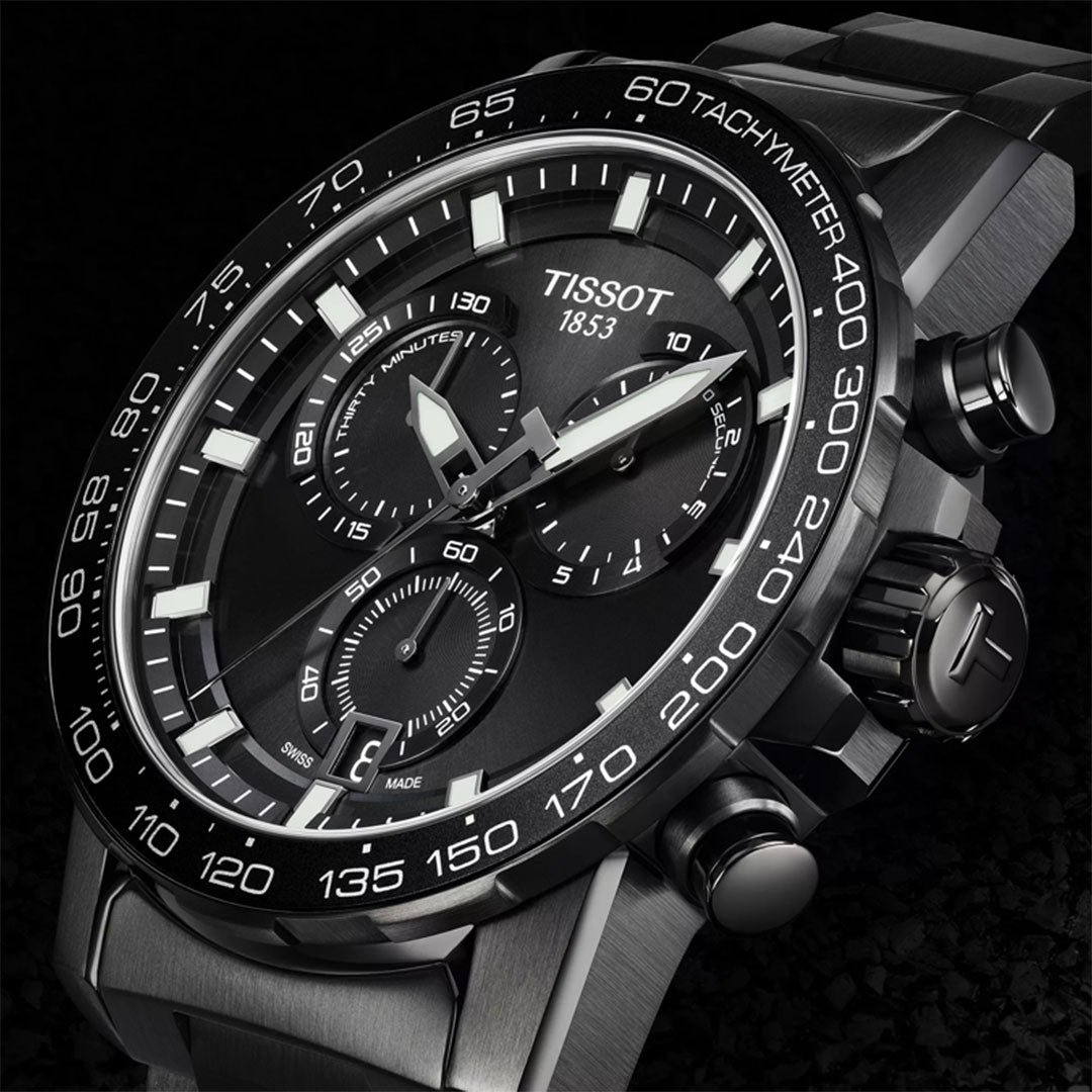 Close-up of a Tissot Supersport Chrono Quartz 45.5mm watch with black dial, white hour markers, three subdials, and a steel case and bracelet by Tissot, displayed on a dark textured background—a top pick for quality watch enthusiasts.