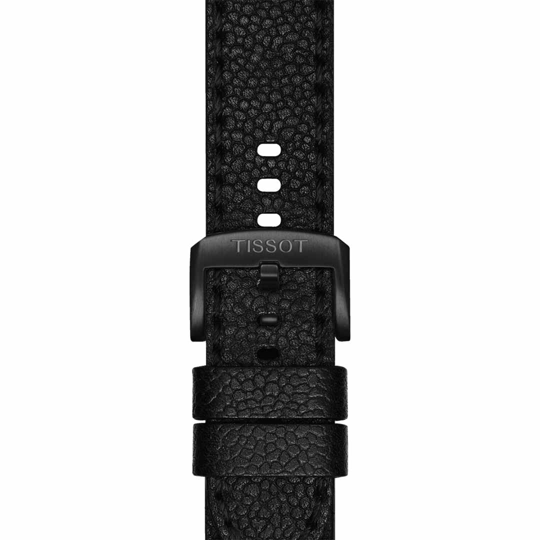 A detailed view of a black leather watch strap featuring a textured finish highlights the precision of Swiss craftsmanship. The metal buckle is engraved with "Tissot." This strap is specifically designed for the Tissot Supersport Chrono Basketball Edition Quartz 45.5mm Watch and offers multiple holes for adjustment.