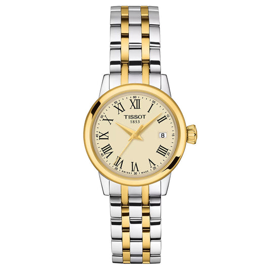 The Tissot Classic Dream Quartz 28mm Watch features a silver and gold two-tone metal band, round gold bezel, cream dial with black Roman numerals, date at 3 o'clock, and "Tissot 1853" on the face for a sophisticated look.