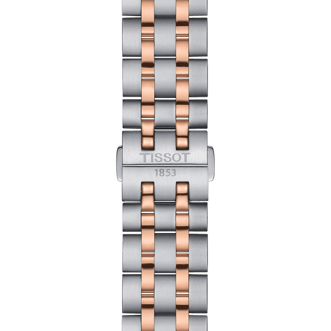 Close-up of the Tissot Classic Dream Quartz 42mm Watch band showcasing a mix of silver and rose gold PVD links. The clasp is engraved with the "Tissot" brand and the year "1853" below it. This sleek, modern design is enhanced by a sturdy stainless steel case.