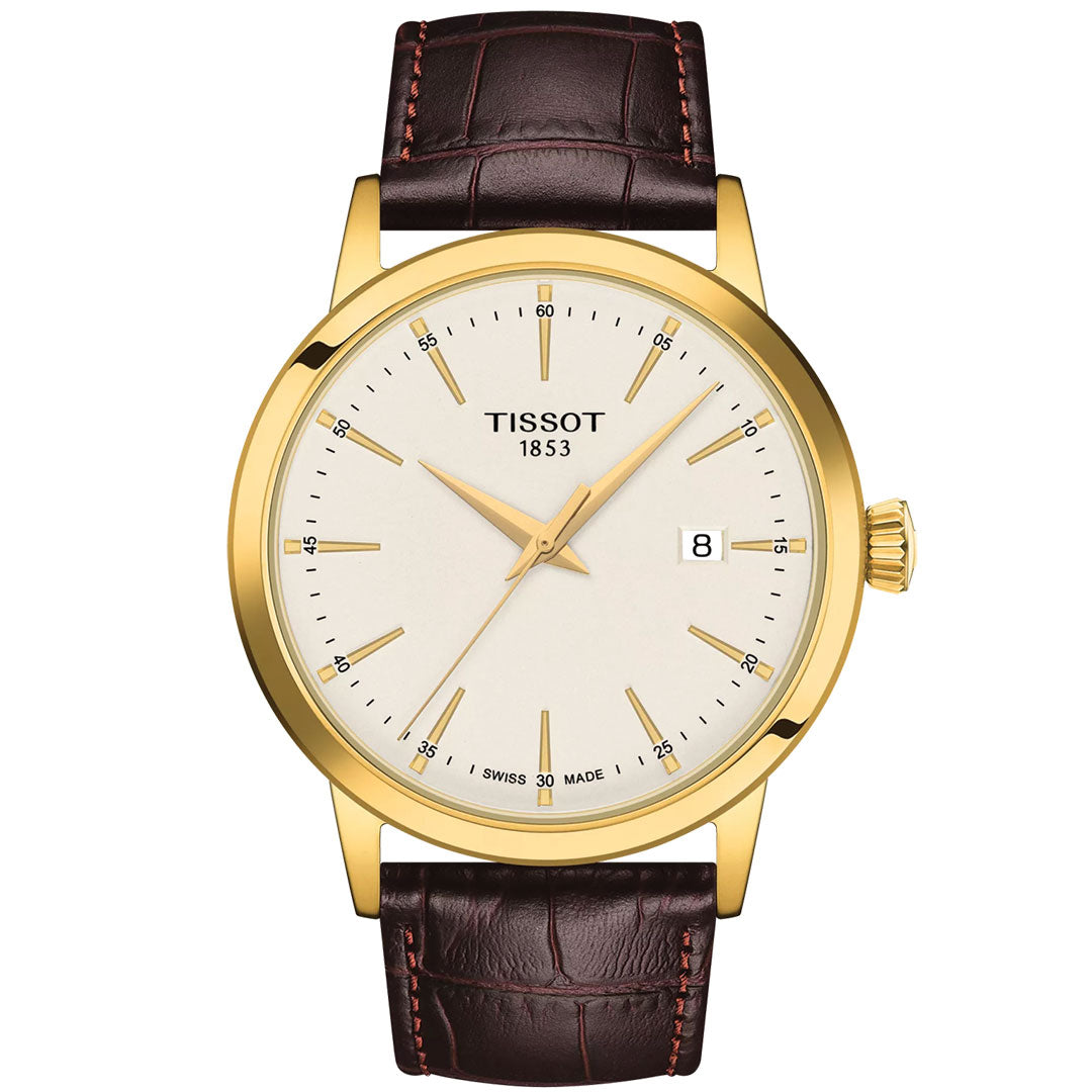 The Tissot Classic Dream Quartz 42mm Watch features a gold case, white dial, brown leather strap, minimalistic design, date window at 3 o’clock, and displays “Tissot 1853” on the face.